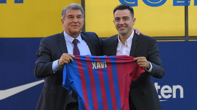 Newly-appointed FC Barcelona's Spanish coach Xavi Hernandez (R), flanked by FC Barcelona's Spanish president Joan Laporta, poses with his jersey during the presentation ceremony at the Camp Nou stadium in Barcelona on November 8, 2021.