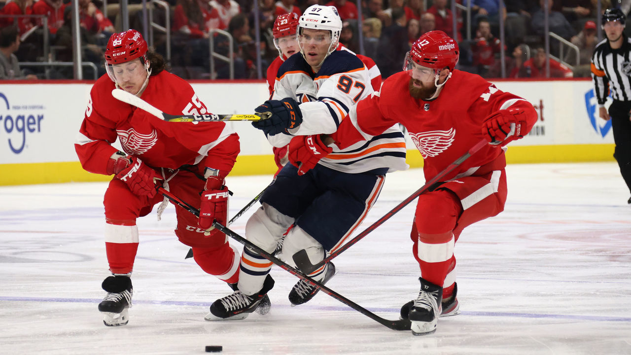 DETROIT, MICHIGAN - NOVEMBER 09: Connor McDavid #97 of the Edmonton Oilers tries to split the defense of Filip Hronek #17 and Tyler Bertuzzi #59 of the Detroit Red Wings during the third period at Little Caesars Arena on November 09, 2021 in Detroit, Michigan. Detroit won the game 4-2.