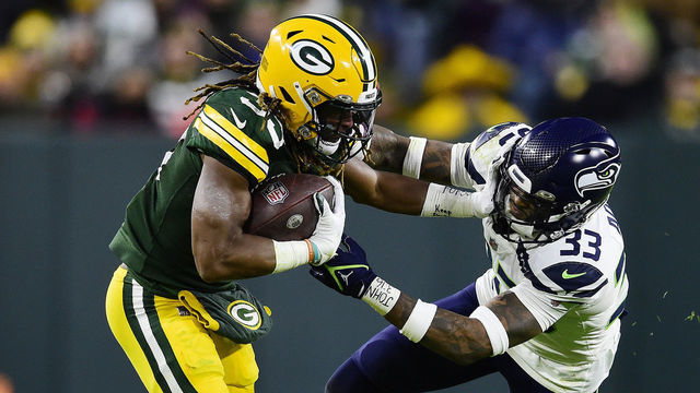 GREEN BAY, WISCONSIN - NOVEMBER 14: Aaron Jones #33 of the Green Bay Packers is tackled by Jamal Adams #33 of the Seattle Seahawks during the first half at Lambeau Field on November 14, 2021 in Green Bay, Wisconsin.
