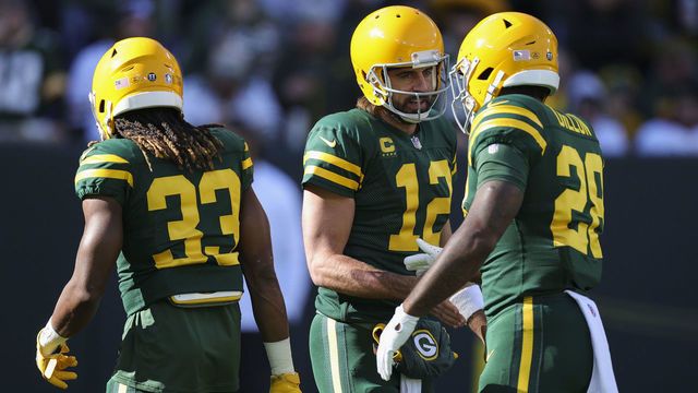 GREEN BAY, WISCONSIN - OCTOBER 24: Aaron Jones #33, Aaron Rodgers #12, and AJ Dillon #28 of the Green Bay Packers meet before the game against the Washington Football Team at Lambeau Field on October 24, 2021 in Green Bay, Wisconsin.