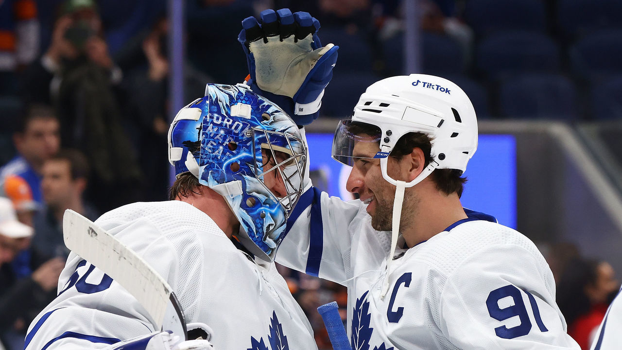 ELMONT, NEW YORK - NOVEMBER 21: John Tavares #91 and Joseph Woll #60 of the Toronto Maple Leafs celebrates after defeating the New York Islanders 3-0 at UBS Arena on November 21, 2021 in Elmont, New York.