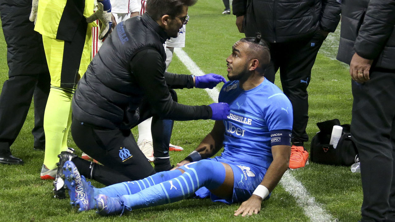 LYON, FRANCE - NOVEMBER 21: The match is stopped after only few minutes when Dimitri Payet of OM - here checked by a doctor - is hit by a plastic bottle of water thrown by a supporter of Lyon during the Ligue 1 Uber Eats match between Olympique Lyonnais (OL) and Olympique de Marseille (OM) at Groupama Stadium on November 21, 2021 in Decines near Lyon, France. . After two hours of waiting, the match is definitely stopped and supporters have to leave the stadium, frustrated.