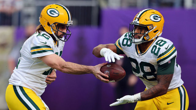 MINNEAPOLIS, MINNESOTA - NOVEMBER 21: Aaron Rodgers #12 of the Green Bay Packers hands the balls off to A.J. Dillon #28 during the game against the Minnesota Vikings in the second half at U.S. Bank Stadium on November 21, 2021 in Minneapolis, Minnesota.