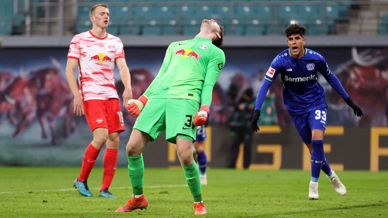28 November 2021, Saxony, Leipzig: Football, Bundesliga, RB Leipzig - Bayer Leverkusen, Matchday 13 at Red Bull Arena. Leipzig goalkeeper Josep Martinez is annoyed after conceding a goal to Leverkusen 3:1. Leverkusen's Piero Hincapie cheers on the right. IMPORTANT NOTE: In accordance with the regulations of the DFL Deutsche Fußball Liga and the DFB Deutscher Fußball-Bund, it is prohibited to use or have used photographs taken in the stadium and/or of the match in the form of sequence pictures and/or video-like photo series. Photo: Jan Woitas/dpa