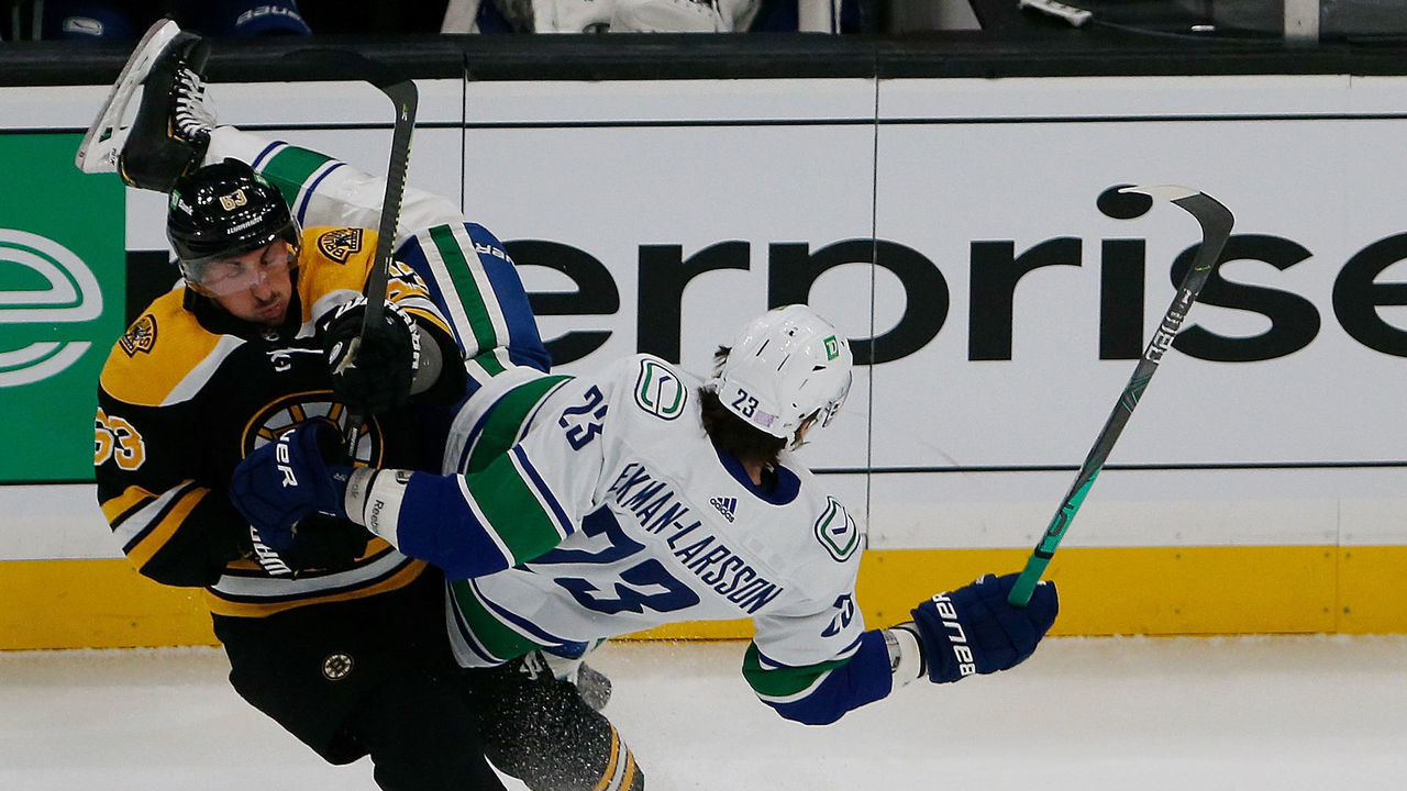 Boston - November 28: Boston Bruins Brad Marchand (L) upends Canucks Oliver Ekman-Larsson during the first period of play. The Boston Bruins host the Vancouver Canucks in a regular season NHL game at TD Garden in Boston on Nov. 28, 2021.