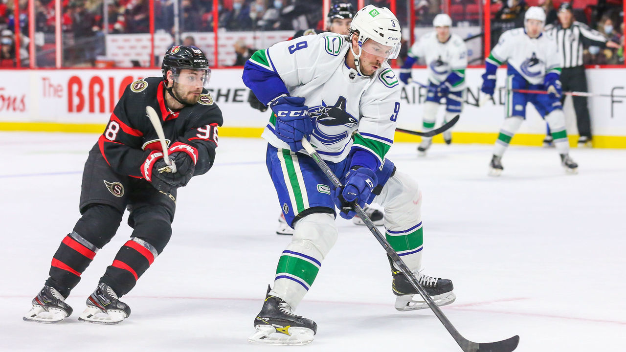 OTTAWA, ONTARIO - DECEMBER 01: J.T. Miller #9 of the Vancouver Canucks carries the puck past Victor Mete #98 of the Ottawa Senators during the third period at Canadian Tire Centre on December 01, 2021 in Ottawa, Ontario.