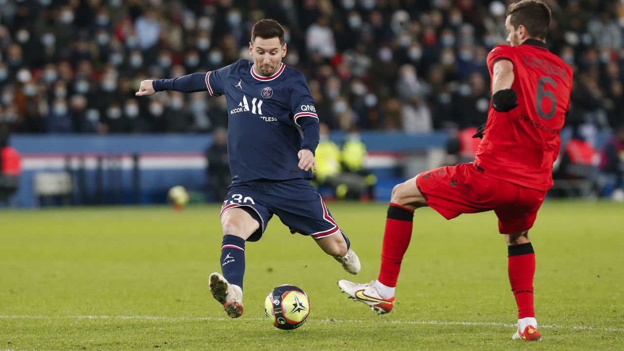 PARIS, FRANCE - DECEMBER 01: Lionel Messi #30 of Paris Saint-Germain shoots the ball against Morgan Schneiderlin #6 of OGC Nice during the Ligue 1 Uber Eats match between Paris Saint Germain and OGC Nice at Parc des Princes on December 1, 2021 in Paris, France.
