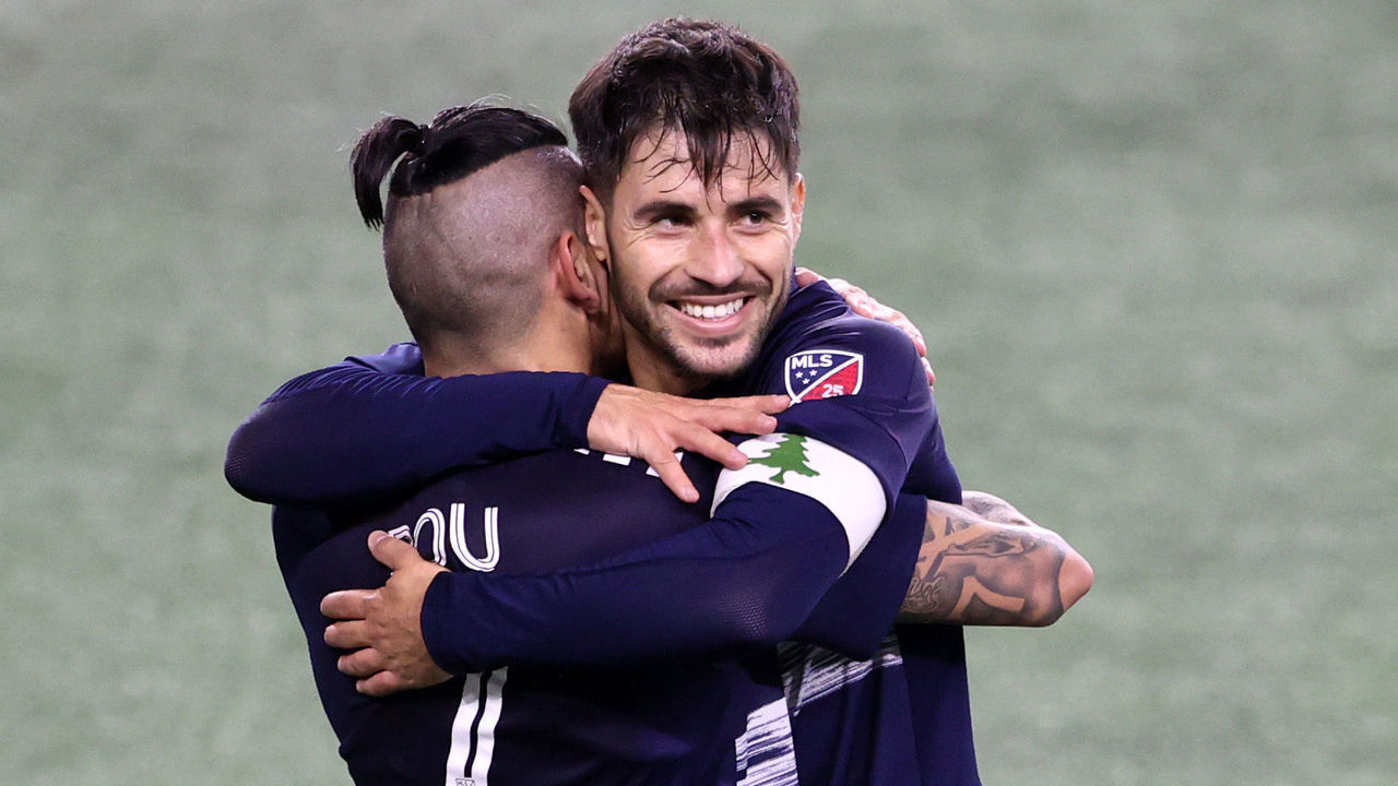 FOXBOROUGH, MASSACHUSETTS - NOVEMBER 20: Gustavo Bou #7 of New England Revolution celebrates with Carles Gil #22 after scoring the game winning goal against the Montreal Impact during second half of the Play-In Round match of the MLS Cup Playoffs at Gillette Stadium on November 20, 2020 in Foxborough, Massachusetts. The Revolution defeat the Impact 2-1.