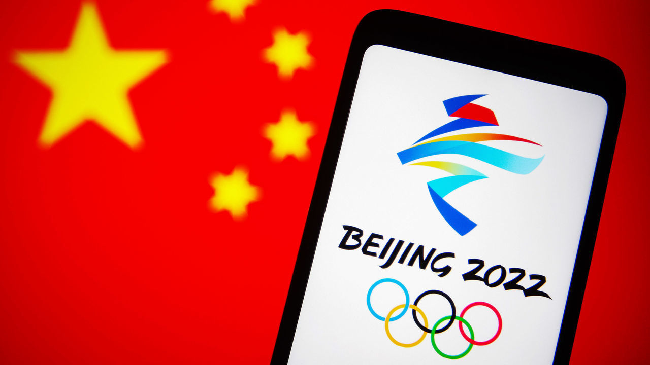 UKRAINE - 2021/12/07: In this photo illustration, the 2022 Winter Olympics (XXIV Olympic Winter Games or Beijing 2022) logo is seen on a smartphone screen with a flag of China in the background. (Photo Illustration by Pavlo Gonchar/SOPA Images/LightRocket via Getty Images)
