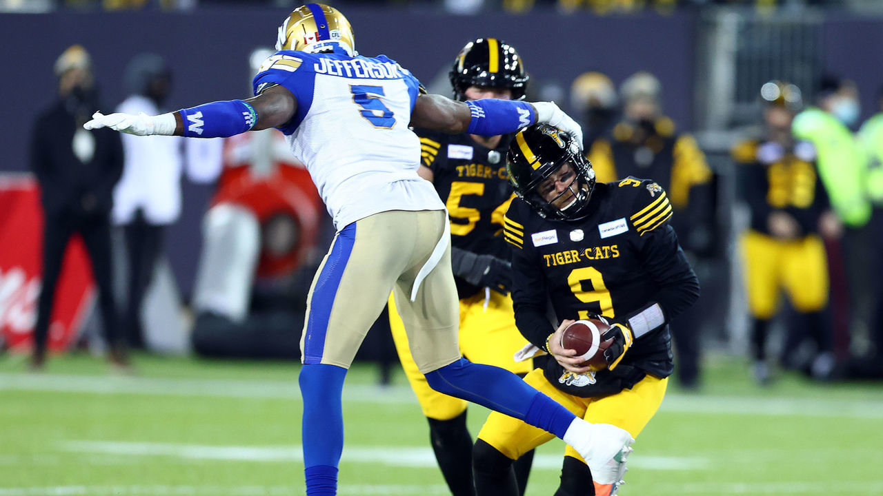 HAMILTON, ON - DECEMBER 12: Dane Evans #9 of the Hamilton Tiger-Cats runs with the ball as Willie Jefferson #5 the Winnipeg Blue Bombers tackles him during the 108th Grey Cup CFL Championship Game at Tim Hortons Field on December 12, 2021 in Hamilton, Ontario, Canada.
