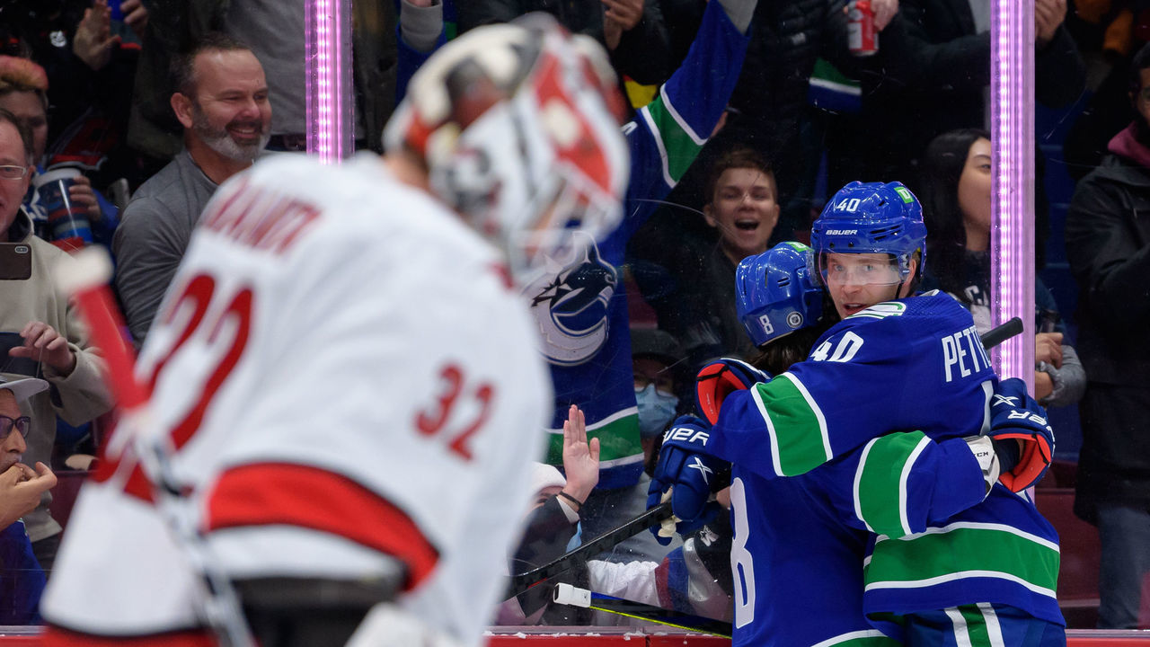 VANCOUVER, BC - DECEMBER 12: Vancouver Canucks center Elias Pettersson (40) is congratulated by right wing Conor Garland (8) after scoring a goal on Carolina Hurricanes goaltender Antti Raanta (32) during their NHL game at Rogers Arena on December 12, 2021 in Vancouver, British Columbia, Canada.