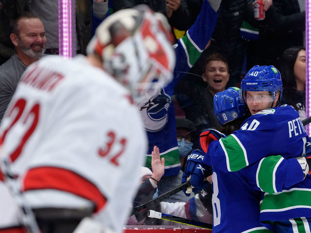 VANCOUVER, BC - DECEMBER 12: Vancouver Canucks center Elias Pettersson (40) is congratulated by right wing Conor Garland (8) after scoring a goal on Carolina Hurricanes goaltender Antti Raanta (32) during their NHL game at Rogers Arena on December 12, 2021 in Vancouver, British Columbia, Canada.