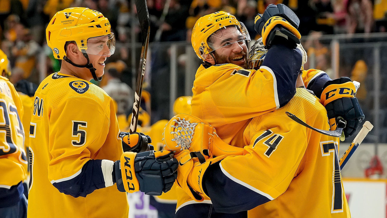NASHVILLE, TN - DECEMBER 16: Luke Kunin #11and Matt Benning #5 congratulates Juuse Saros #74 of the Nashville Predators on a 5-2 win against the Colorado Avalanche during an NHL game at Bridgestone Arena on December 16, 2021 in Nashville, Tennessee.