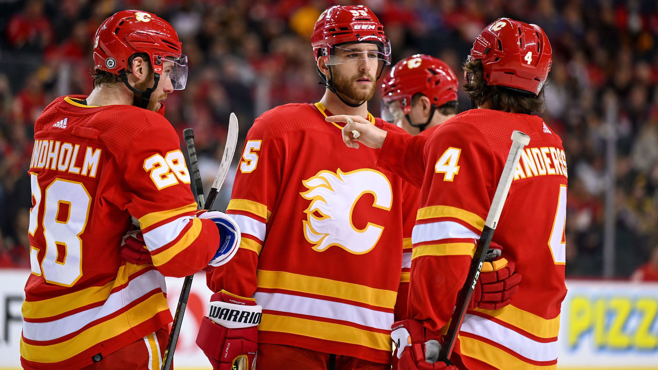 CALGARY, AB - DECEMBER 11: Calgary Flames Center Elias Lindholm (28), Calgary Flames Defenceman Noah Hanifin (55) and Calgary Flames Defenceman Rasmus Andersson (4) talk strategy during the second period of an NHL game where the Calgary Flames hosted the Boston Bruins on December 11, 2021, at the Scotiabank Saddledome in Calgary, AB.