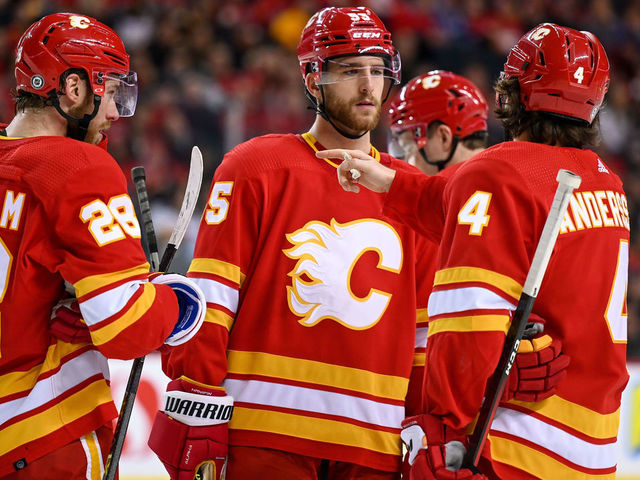 CALGARY, AB - DECEMBER 11: Calgary Flames Center Elias Lindholm (28), Calgary Flames Defenceman Noah Hanifin (55) and Calgary Flames Defenceman Rasmus Andersson (4) talk strategy during the second period of an NHL game where the Calgary Flames hosted the Boston Bruins on December 11, 2021, at the Scotiabank Saddledome in Calgary, AB.