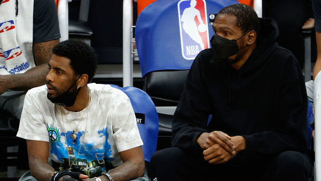 PHOENIX, ARIZONA - FEBRUARY 16: Kyrie Irving #11 and Kevin Durant #7 of the Brooklyn Nets watch from the bench during the first half of the NBA game against the Phoenix Suns at Phoenix Suns Arena on February 16, 2021 in Phoenix, Arizona.