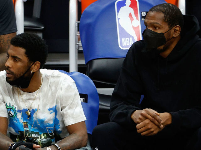 PHOENIX, ARIZONA - FEBRUARY 16: Kyrie Irving #11 and Kevin Durant #7 of the Brooklyn Nets watch from the bench during the first half of the NBA game against the Phoenix Suns at Phoenix Suns Arena on February 16, 2021 in Phoenix, Arizona.