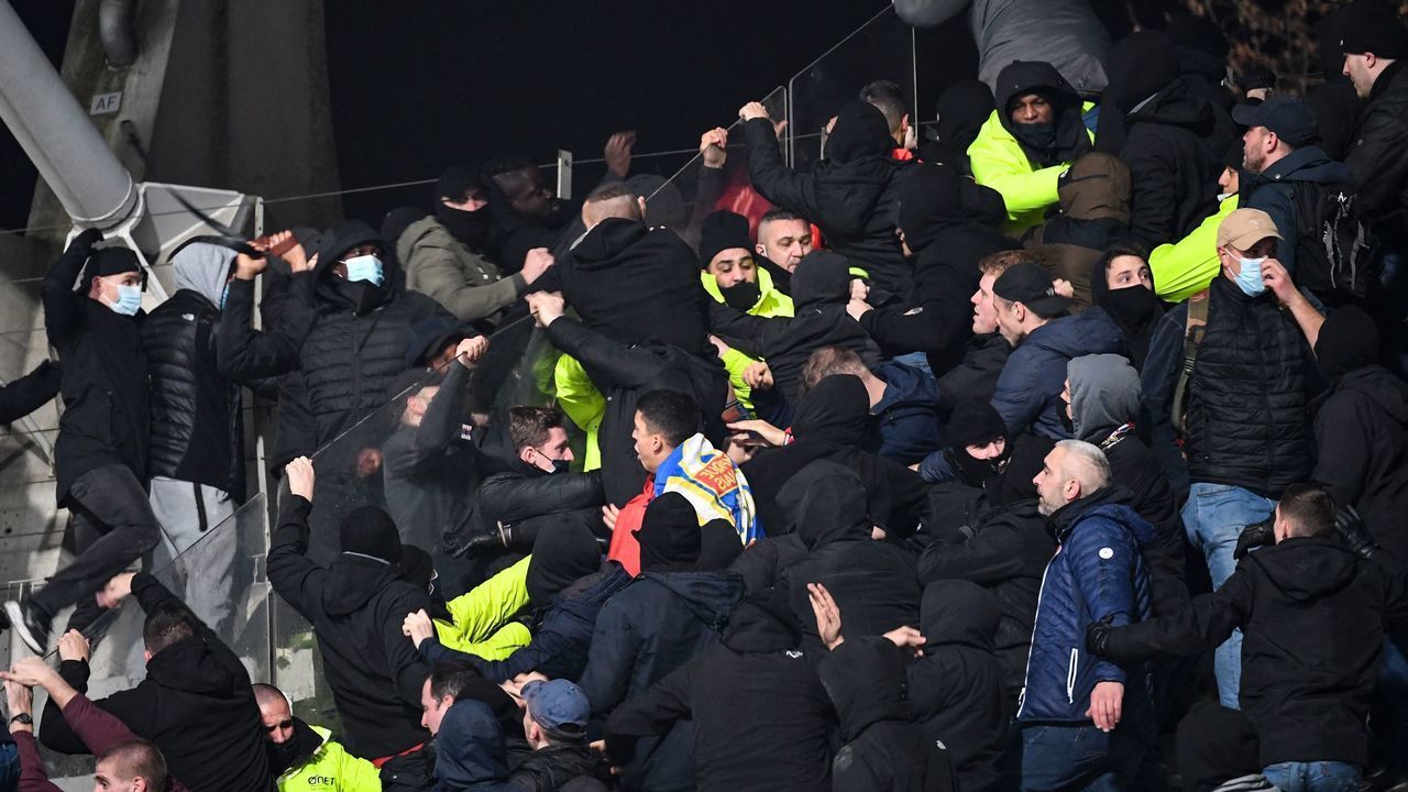 Security staff members intervene in the stands at half-time as supporters clash during the French Cup round of 64 football match between Paris FC and Olympique Lyonnais (OL) at the Charlety stadium in Paris, on December 17, 2021. - The match was interrupted due to incidents in the stands. At half-time, several flares were launched toward Lyon supporters, and two improvised explosive devices also exploded. Spectators from this stand then descended on the lawn to move away from the scene of the incidents, preventing the resumption of the match.
