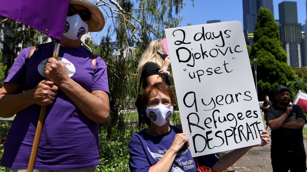 An activist holds a placard during a rally outside a government detention centre where Serbia's tennis champion Novak Djokovic is staying in Melbourne on January 9, 2022, in support of refugees detained at the centre.
