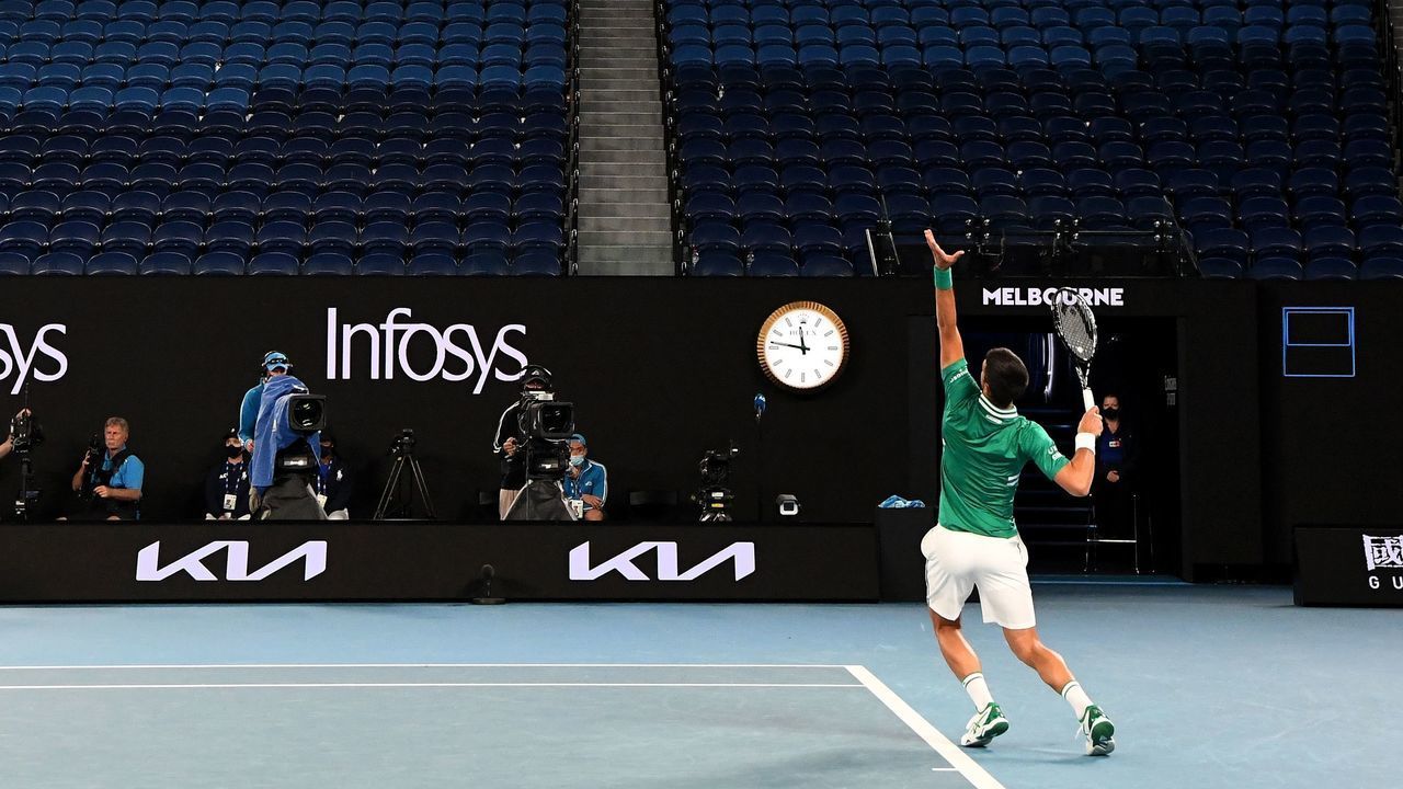 Empty seats are pictured in the background as Serbia's Novak Djokovic serves against Taylor Fritz of the US during their men's singles match on day five of the Australian Open tennis tournament in Melbourne on February 12, 2021.