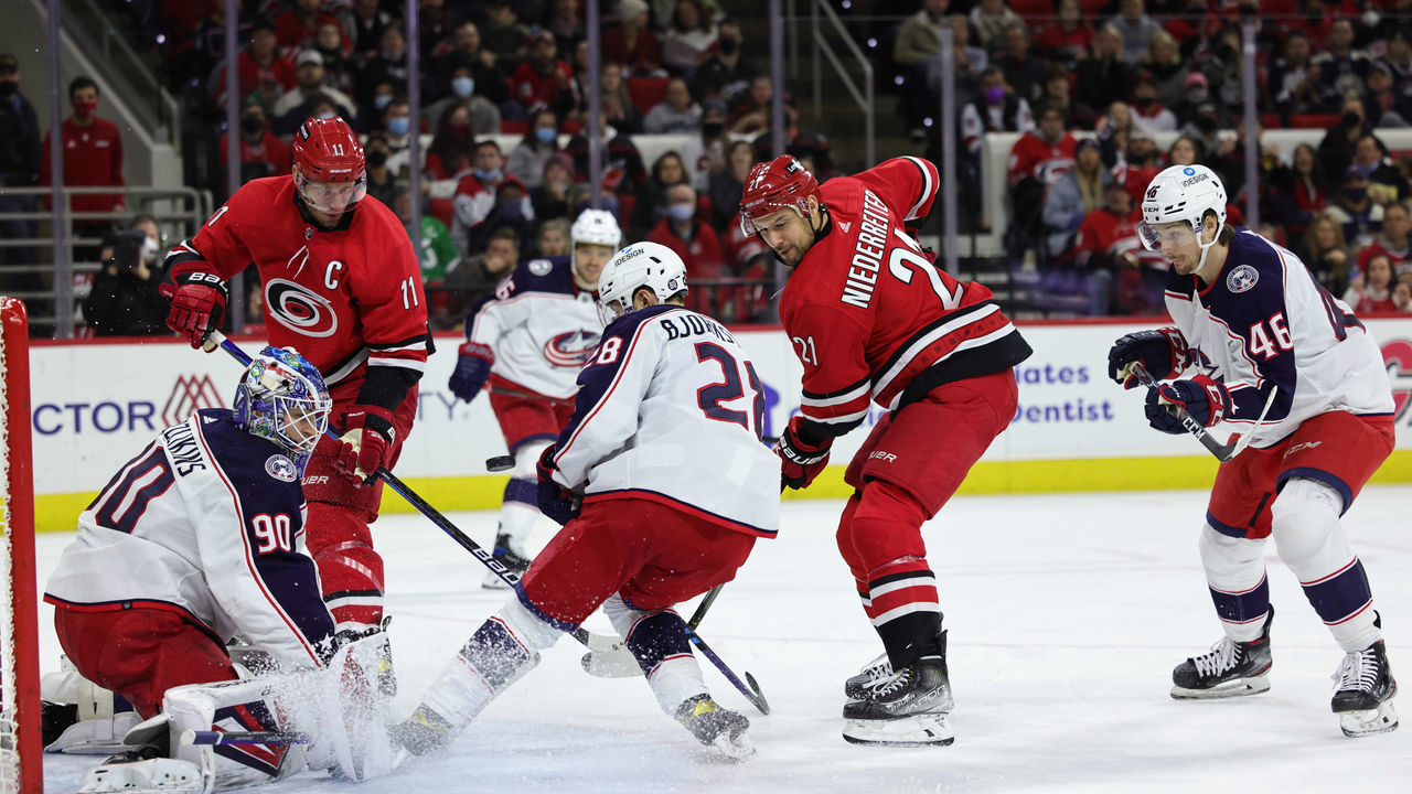 RALEIGH, NC - JANUARY 13: Carolina Hurricanes center Jordan Staal #11 looks for a rebound as Columbus Blue Jackets goaltender Elvis Merzlikins #90 keeps his eye on the puck as Columbus Blue Jackets right wing Oliver Bjorkstrand #28 defends during an NHL game on January 13, 2022 at PNC Arena in Raleigh, North Carolina.