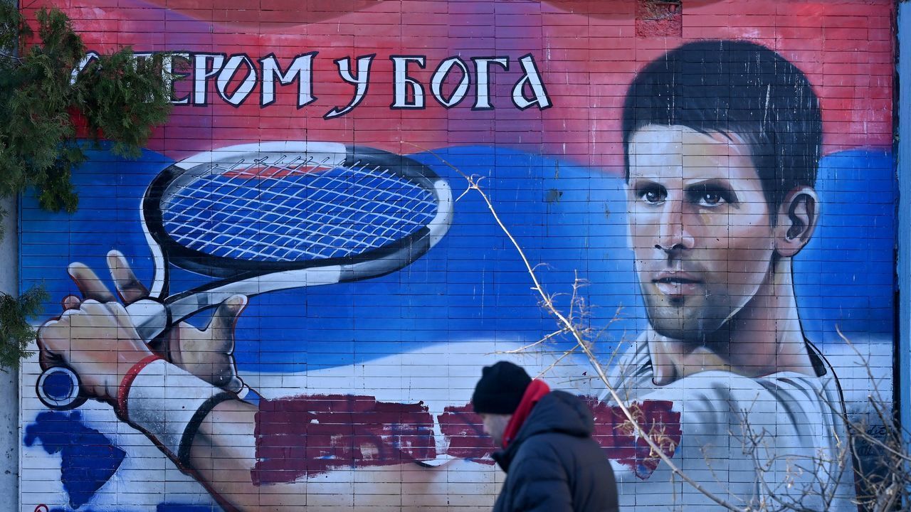A local resident walks past a mural depicting Serbian tennis player Novak Djokovic in Belgrade on January 16, 2022. - Tennis star Novak Djokovic on January 16, 2022 lost his fight against deportation from Australia many in his native Serbia reacted with fury to a federal court ruling calling it a "shameful farce". Three judges at the Australian Federal Court unanimously dismissed the unvaccinated world number one's last-gasp attempt to overturn the government's cancellation of his visa.
