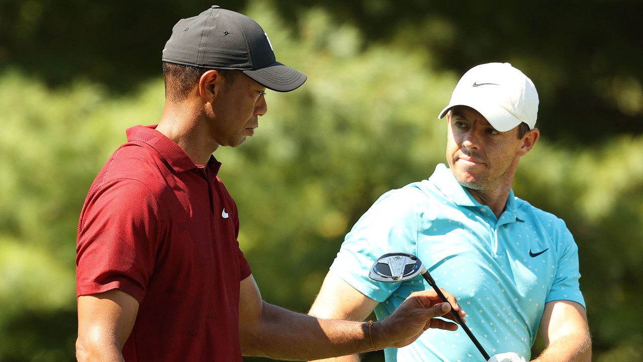 NORTON, MASSACHUSETTS - AUGUST 23: Rory McIlroy (R) of Northern Ireland hands his driver to Tiger Woods (L) of the United States as they walk off the tenth tee during the final round of The Northern Trust at TPC Boston on August 23, 2020 in Norton, Massachusetts.