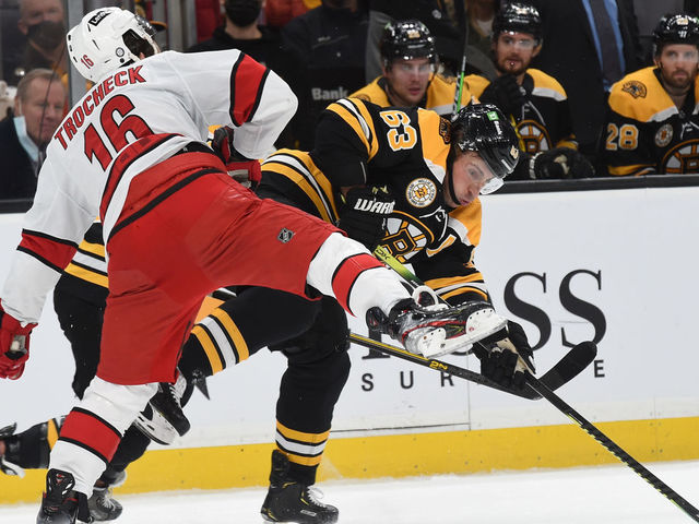 BOSTON, MA - JANUARY 18: Brad Marchand #63 of the Boston Bruins passes the puck against Vincent Trocheck #16 of the Carolina Hurricanes at the TD Garden on January 18, 2022 in Boston, Massachusetts.