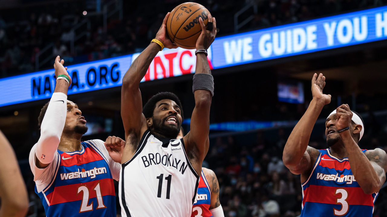 WASHINGTON, DC - JANUARY 19: Kyrie Irving #11 of the Brooklyn Nets goes to the basket against Daniel Gafford #21 and Bradley Beal #3 of the Washington Wizards during the first half at Capital One Arena on January 19, 2022 in Washington, DC.