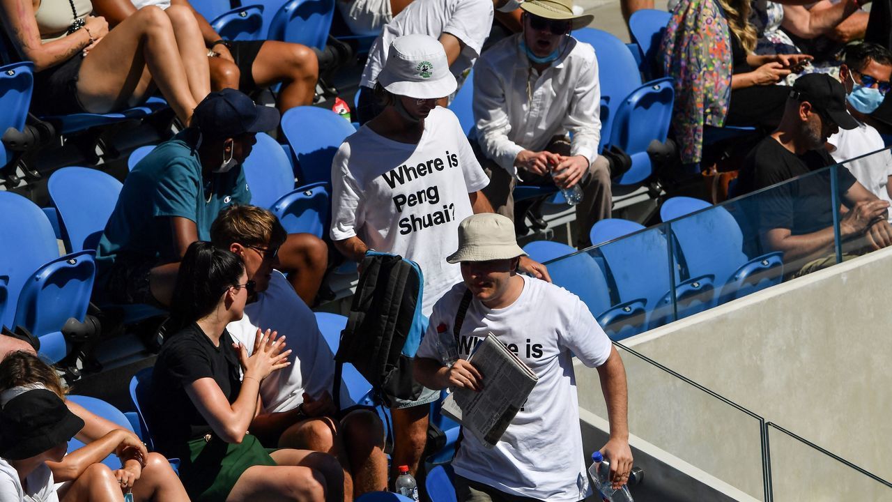 Two spectators wearing "Where is Peng Shuai?" T-shirts, referring to the former doubles world number one from China, are pictured in the stands on day nine of the Australian Open tennis tournament in Melbourne on January 25, 2022. - -- IMAGE RESTRICTED TO EDITORIAL USE - STRICTLY NO COMMERCIAL USE --