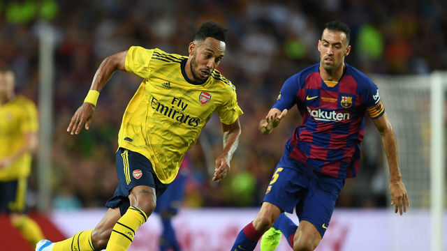 BARCELONA, SPAIN - AUGUST 04: Pierre-Emerick Aubameyang of Arsenal takes on Sergio Busquets of Barcleona during the match between FC Barcelona and Arsenal at Nou Camp on August 04, 2019 in Barcelona, Spain.