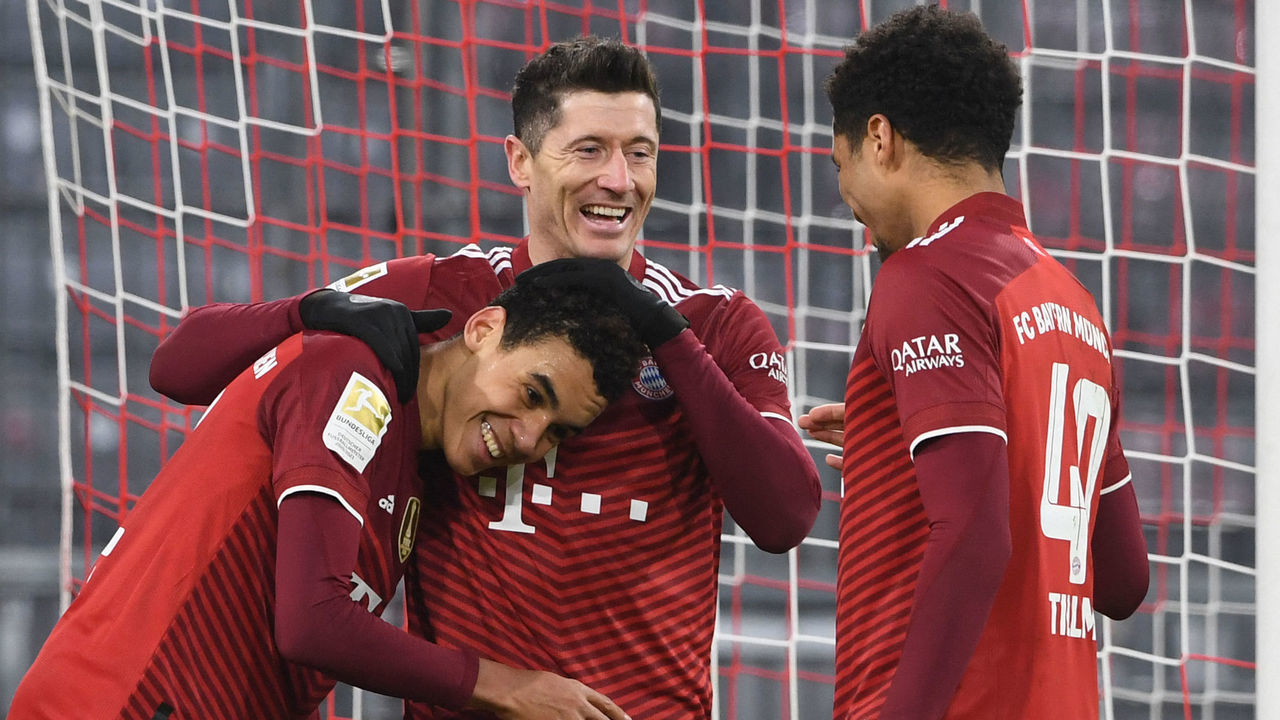 TOPSHOT - Bayern Munich's Polish forward Robert Lewandowski (C) celebrates scoring the 4-0 with Bayern Munich's German midfielder Jamal Musiala (L) and Bayern Munich's German midfielder Malik Tillman during the German first division Bundesliga football match Bayern Munich vs VfL Wolfsburg in Munich, southern Germany, on December 17, 2021. - DFL REGULATIONS PROHIBIT ANY USE OF PHOTOGRAPHS AS IMAGE SEQUENCES AND/OR QUASI-VIDEO