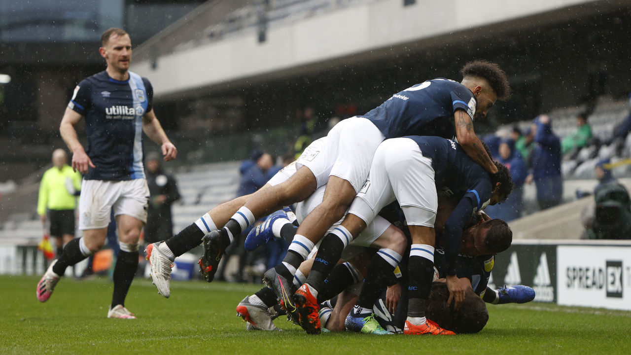 LONDON, ENGLAND - FEBRUARY 19: Players of Huddersfield Town pile on top of each other whilst celebrating during the Sky Bet Championship match between Fulham and Huddersfield Town at Craven Cottage on February 19, 2022 in London, England.
