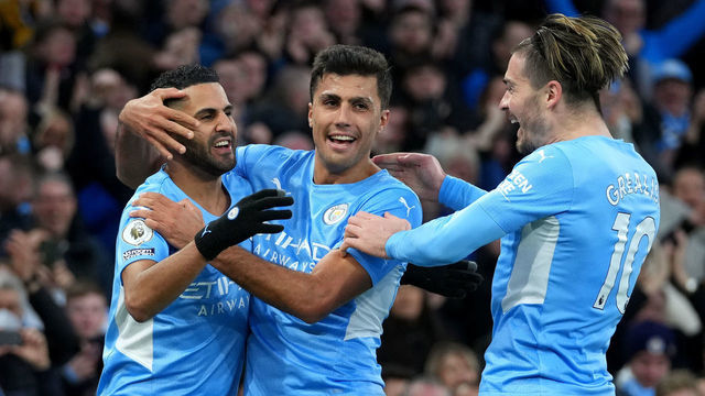 MANCHESTER, ENGLAND - MARCH 06: Riyad Mahrez of Manchester City celebrates their sides third goal with team mates Rodrigo and Jack Grealish during the Premier League match between Manchester City and Manchester United at Etihad Stadium on March 06, 2022 in Manchester, England.