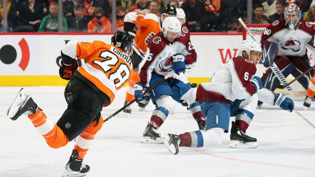 PHILADELPHIA, PA - DECEMBER 06: Claude Giroux #28 of the Philadelphia Flyers shoots the puck between Logan O Connor #25 and Erik Johnson #6 of the Colorado Avalanche at the Wells Fargo Center on December 6, 2021 in Philadelphia, Pennsylvania.