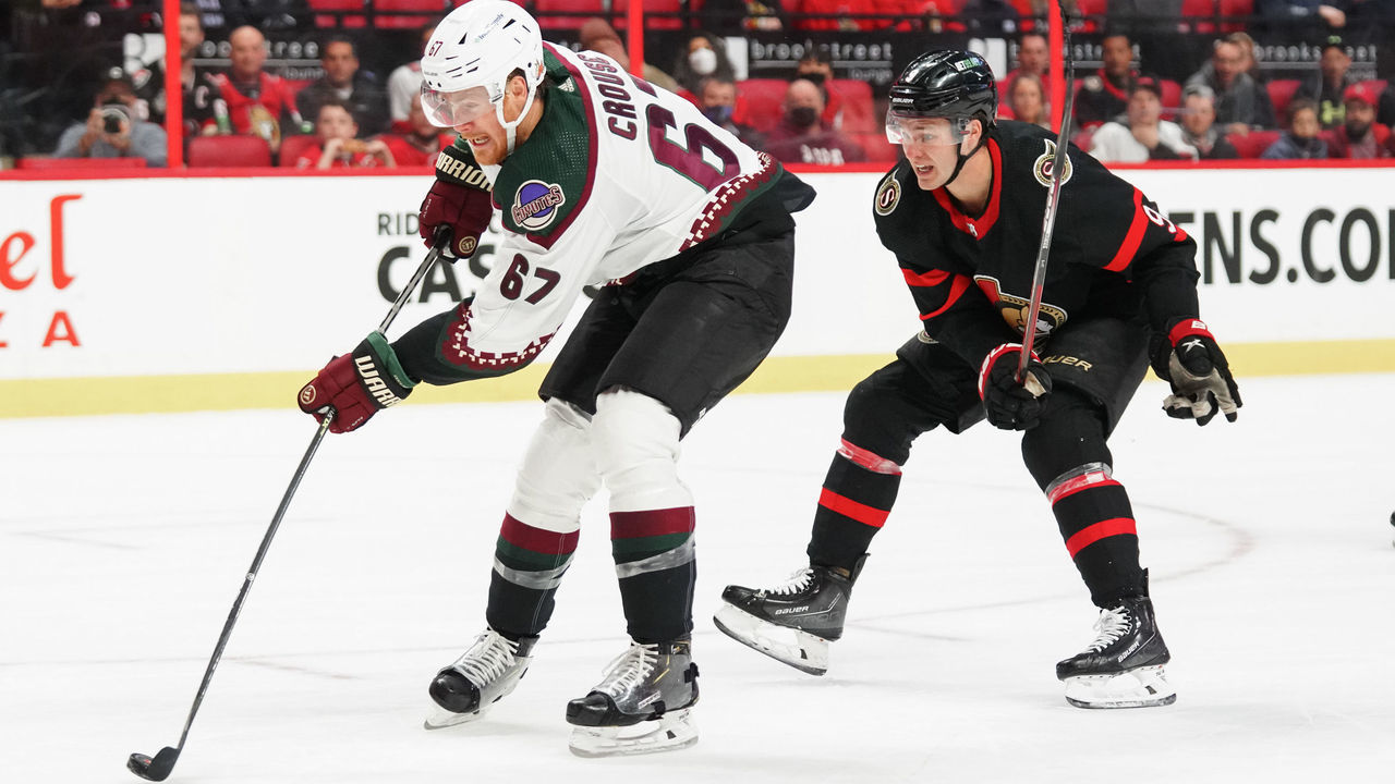 OTTAWA, ON - MARCH 14: Lawson Crouse #67 of the Arizona Coyotes shoots the puck for a shorthanded goal (his third marker of the game), as Josh Norris #9 of the Ottawa Senators chases on the play at Canadian Tire Centre on March 14, 2022 in Ottawa, Ontario, Canada.