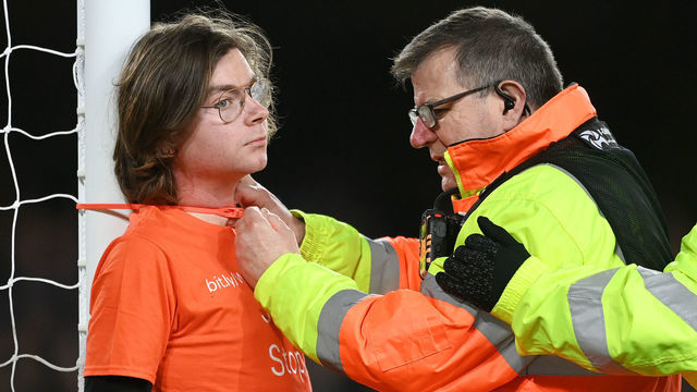 LIVERPOOL, ENGLAND - MARCH 17: A steward attempts to cut cable ties after a fan ties himself to the net in protest during the Premier League match between Everton and Newcastle United at Goodison Park on March 17, 2022 in Liverpool, England.