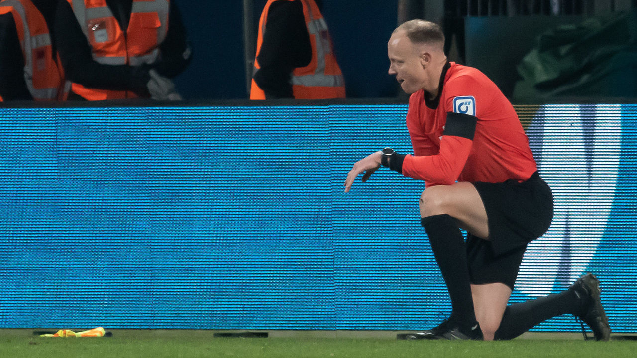 18 March 2022, North Rhine-Westphalia, Bochum: Soccer: Bundesliga, VfL Bochum - Bor. Mönchengladbach, Matchday 27, Vonovia Ruhrstadion. Assistant referee Christian Gittelmann lost his flag and was kneeling on the turf after taking a cup to the head. The linesman was taken to hospital after the match was subsequently abandoned. Photo: Bernd Thissen/dpa