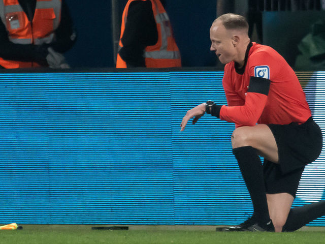 18 March 2022, North Rhine-Westphalia, Bochum: Soccer: Bundesliga, VfL Bochum - Bor. Mönchengladbach, Matchday 27, Vonovia Ruhrstadion. Assistant referee Christian Gittelmann lost his flag and was kneeling on the turf after taking a cup to the head. The linesman was taken to hospital after the match was subsequently abandoned. Photo: Bernd Thissen/dpa