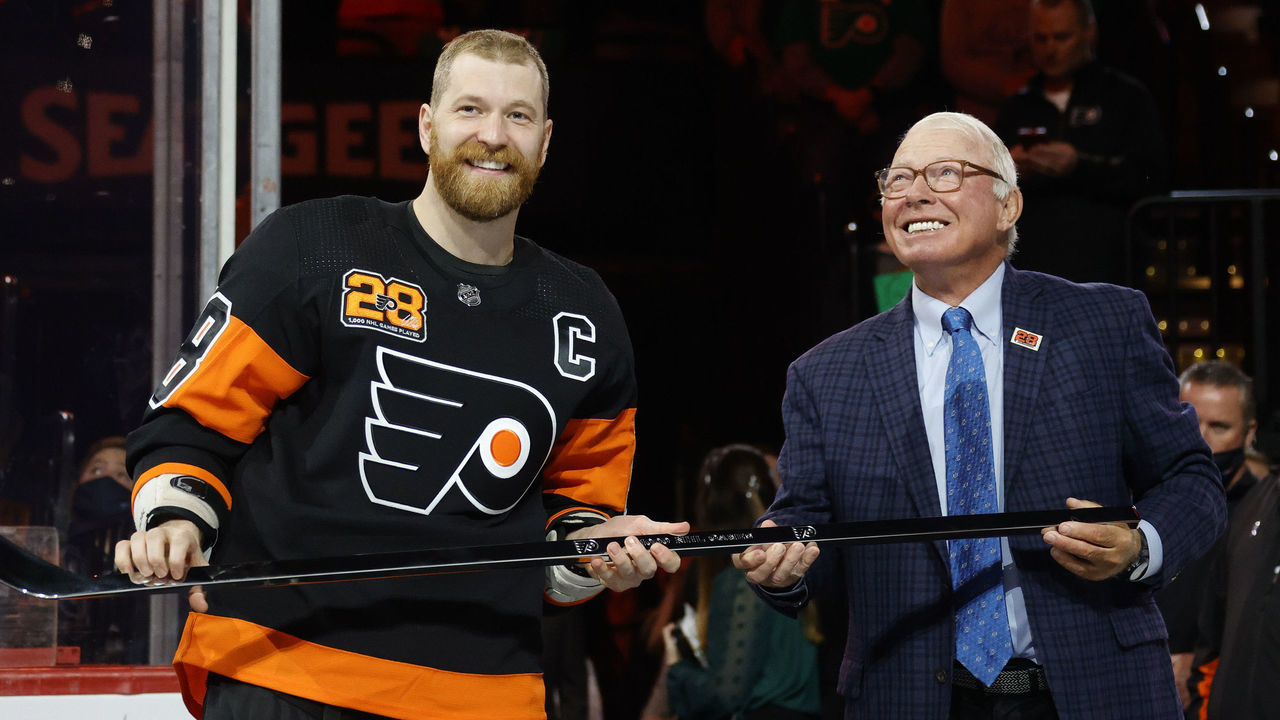 PHILADELPHIA, PENNSYLVANIA - MARCH 17: Claude Giroux #28 of the Philadelphia Flyers is awarded with a commemorative stick by NHL Hall of Fame member and former Flyer Bobby Clarke before a game between the Philadelphia Flyers and the Nashville Predators at Wells Fargo Center on March 17, 2022 in Philadelphia, Pennsylvania. Giroux is playing in his 1,000th-career NHL game.