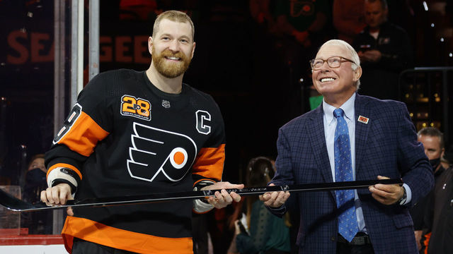 PHILADELPHIA, PENNSYLVANIA - MARCH 17: Claude Giroux #28 of the Philadelphia Flyers is awarded with a commemorative stick by NHL Hall of Fame member and former Flyer Bobby Clarke before a game between the Philadelphia Flyers and the Nashville Predators at Wells Fargo Center on March 17, 2022 in Philadelphia, Pennsylvania. Giroux is playing in his 1,000th-career NHL game.