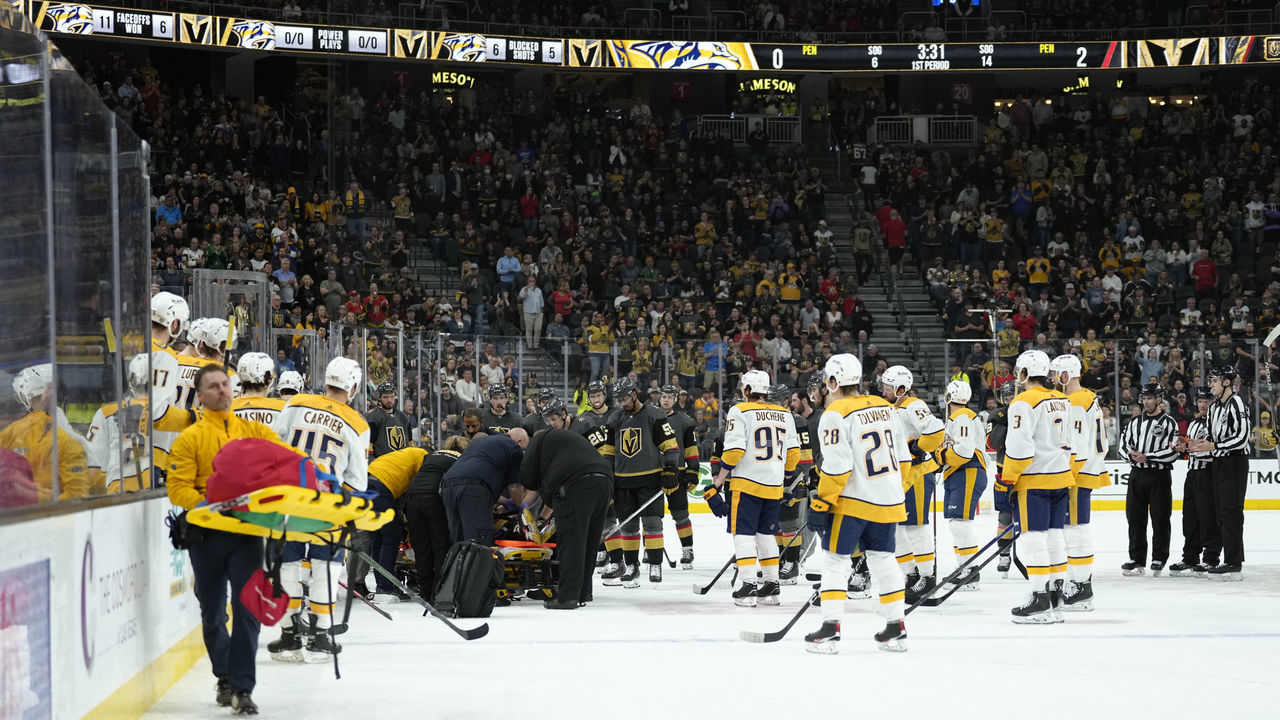 LAS VEGAS, NEVADA - MARCH 24: Vegas Golden Knights and Nashville Predators players look on as Brett Howden #21 of the Vegas Golden Knights receives treatment after crashing into the boards during the first period of a game at T-Mobile Arena on March 24, 2022 in Las Vegas, Nevada.