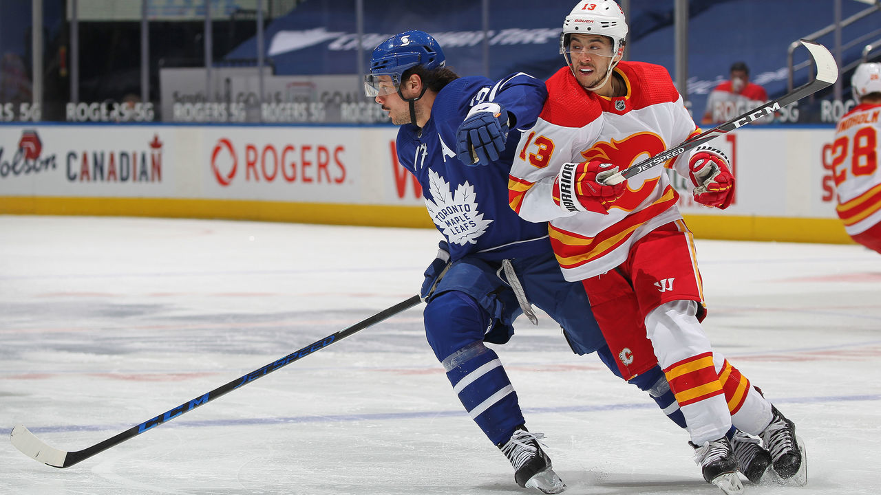 TORONTO, ON - APRIL 13: Johnny Gaudreau #13 of the Calgary Flames battles against Auston Matthews #34 of the Toronto Maple Leafs during an NHL game at Scotiabank Arena on April 13, 2021 in Toronto, Ontario, Canada.