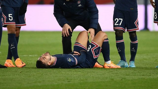 Paris Saint-Germain's Argentinian midfielder Leandro Paredes (C) reacts on the ground following an injury during the French L1 football match between Paris Saint-Germain (PSG) and FC Lorient at the Parc des Princes stadium in Paris on April 3, 2022.