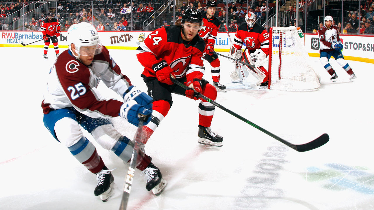 NEWARK, NEW JERSEY - MARCH 08: Ty Smith #24 of the New Jersey Devils skates against Logan O'Connor #25 of the Colorado Avalanche at the Prudential Center on March 08, 2022 in Newark, New Jersey.