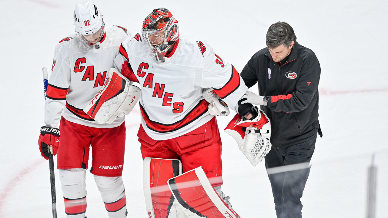 DENVER, COLORADO - APRIL 16: Frederik Andersen #31 of the Carolina Hurricanes is helped off the ice by teammate Jesperi Kotkaniemi #82 and a trainer in the third period of a game against the Colorado Avalanche at Ball Arena on April 16, 2022 in Denver, Colorado.