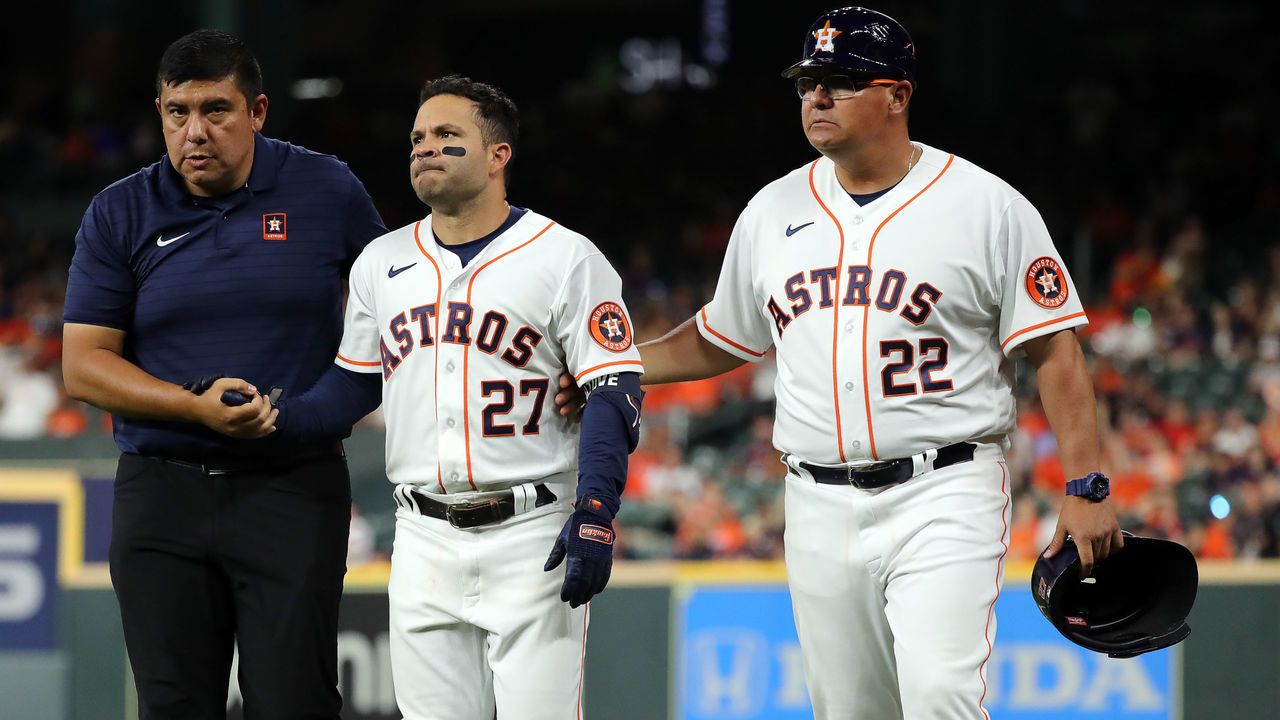 HOUSTON, TEXAS - APRIL 18: Jose Altuve #27 of the Houston Astros is helped off the field by first base coach Omar Lopez #22 and a trainer after injuring himself running out an infield hit in the eighth inning against the Los Angeles Angels at Minute Maid Park on April 18, 2022 in Houston, Texas.