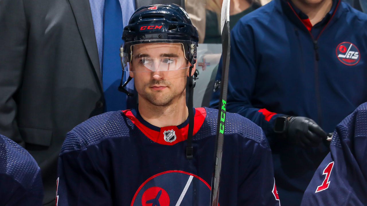 WINNIPEG, MB - APRIL 02: Neal Pionk #4 of the Winnipeg Jets looks on from the bench prior to NHL action against the Los Angeles Kings at Canada Life Centre on April 02, 2022 in Winnipeg, Manitoba, Canada.