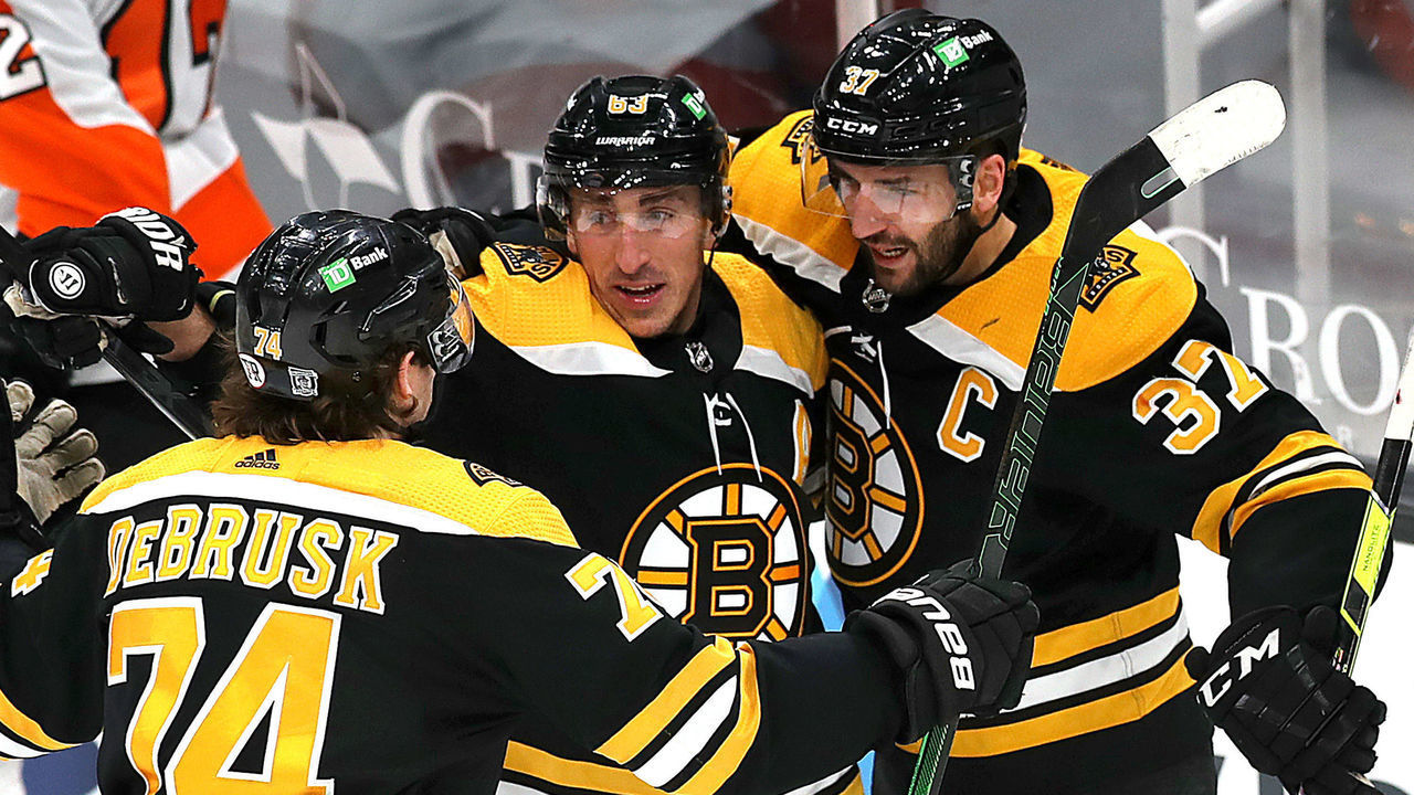 BOSTON - JANUARY 23: Boston Bruins left wing Brad Marchand (63 ) is congratulated by Jake DeBrusk (left) and Patrice Bergeron who both assisted on the goal during the teams home season opener against the Philadelphia Flyers at TD Garden on January 21, 2021 in Boston.