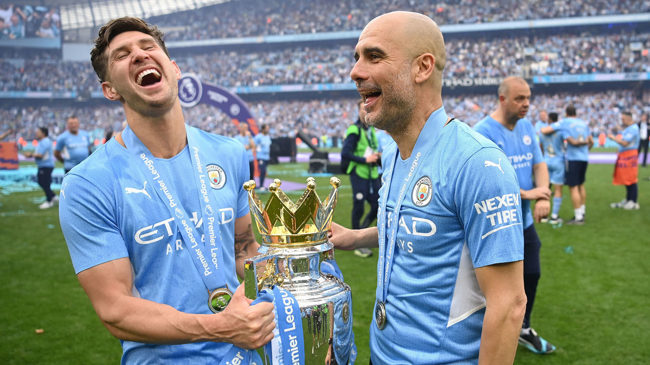 MANCHESTER, ENGLAND - MAY 22: John Stones and Pep Guardiola, Manager of Manchester City celebrate with the Premier League trophy after their side finished the season as Premier League champions during the Premier League match between Manchester City and Aston Villa at Etihad Stadium on May 22, 2022 in Manchester, England.